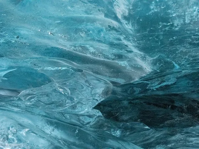Nahaufnahme des glatten, geriffelten blauen Eises eines Gletschers.