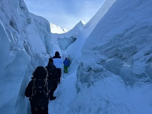 Wanderer spazieren durch eine schmale Gletscherspalte in einem schneebedeckten Gletscher.