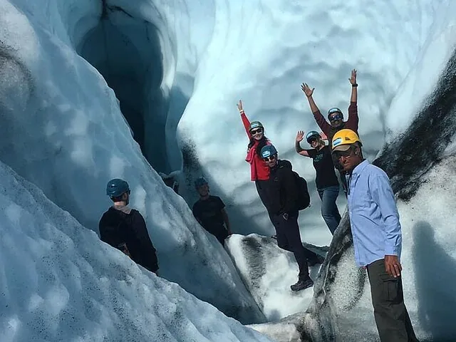 A group of people exploring an ice formation on a glacier.