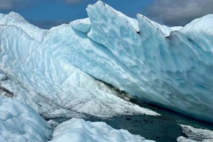 Close-up of a massive, textured wall of blue glacial ice.